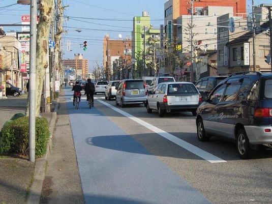 車道に青色カラー舗装したところを走行する自転車